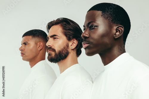 Group of diverse young men with glowing skin standing together in a studio