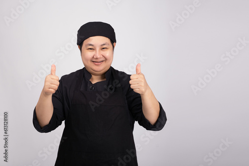 Portrait of smiling chef wearing uniform on gray background.