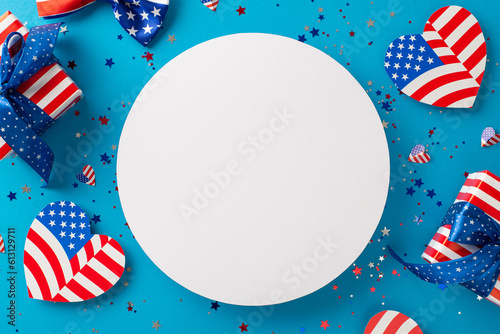Celebrating American spirit. Top-down view of symbolic ornaments, hearts with stars and stripes, confetti, gift boxes wrapped beautifully, all on blue backdrop with empty circle for text or promotion