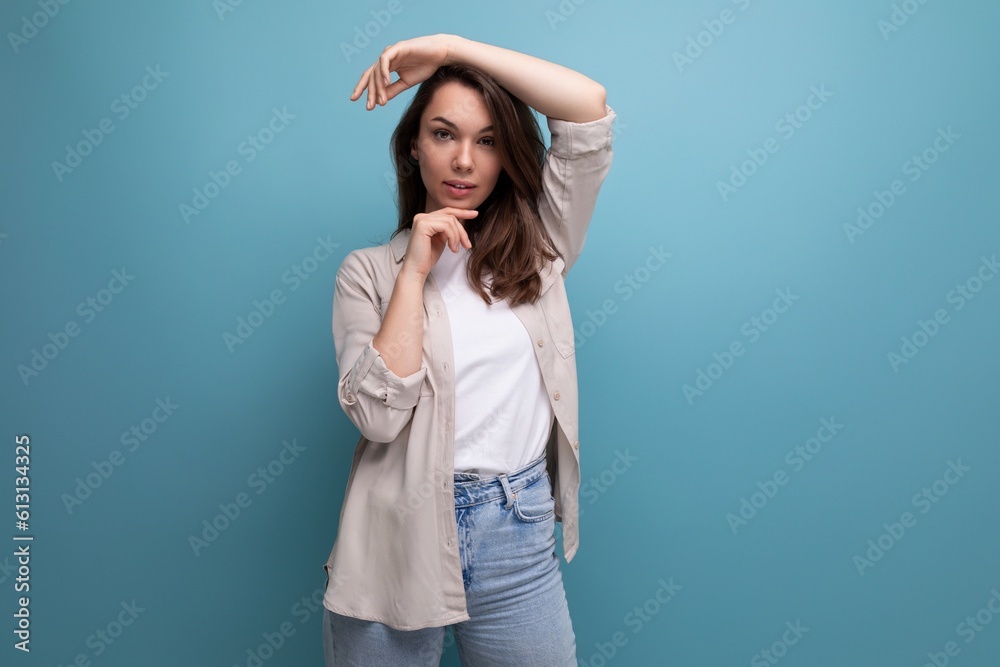 European model appearance young dark-haired lady in informal clothes posing against a blue background European model appearance young dark-haired lady in informal clothes posing against a blue background
