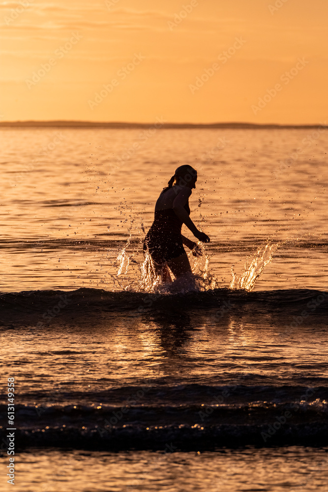 Silhouette of female swimmer having a splash in the Atlantic ocean in Ireland