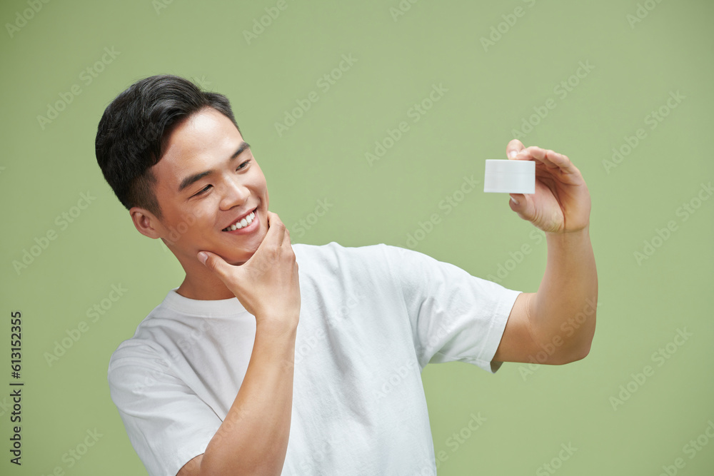 Portrait of young Asian man with cosmetics bottle Portrait of young Asian man with cosmetics bottle