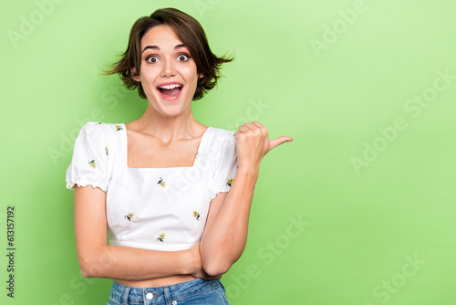 Photo of cute impressed lady wear white blouse open mouth pointing thumb empty space isolated green color background