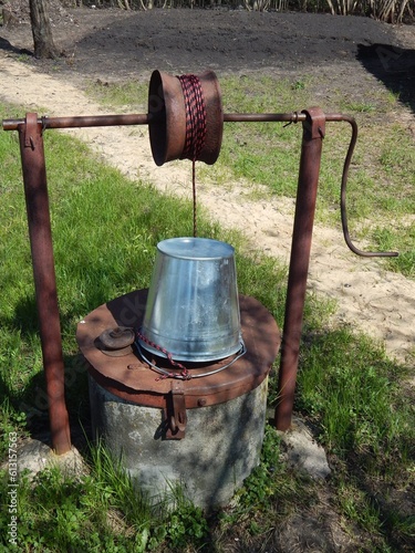 Rural well with clean water. A zinc bucket tied to a well of water.