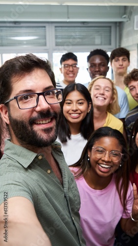 Happy selfie of young group of Erasmus students taking a photo with their teacher in the classroom.