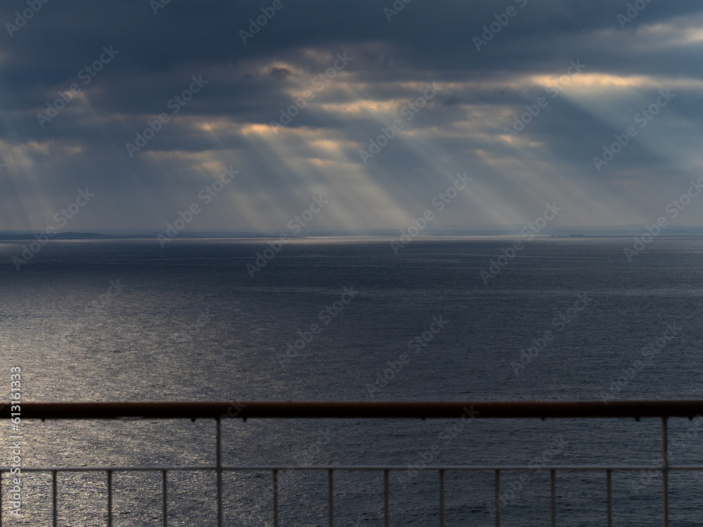 Sonnenaufgang hinter Wolken, beobachtet vom Deck eines Schiffes auf hoher See