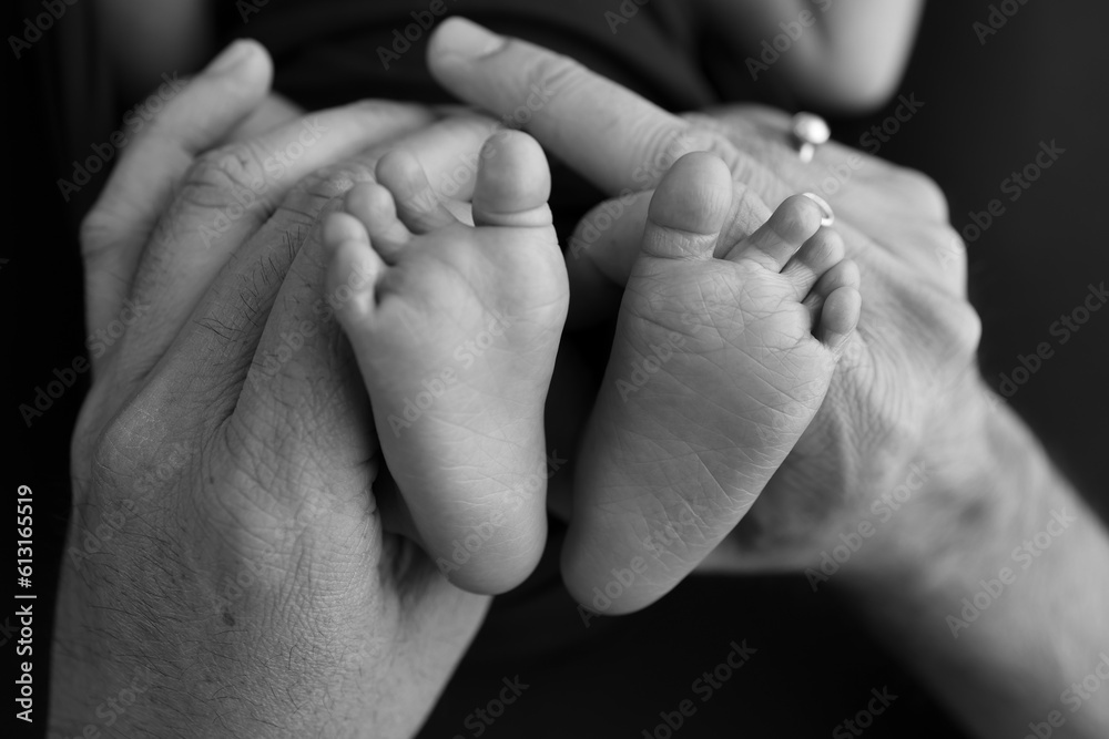 Black white shade beautiful shape hands of mother, hold tiny newborn baby feet on black background Black white shade beautiful shape hands of mother, hold tiny newborn baby feet on black background