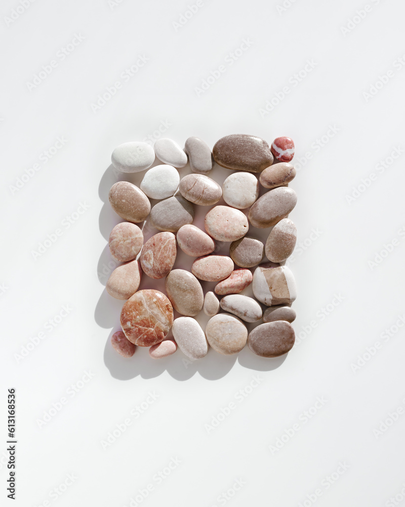 Top view close up colored pebbles sea stones with dark shadows on white background. Creative Square pattern from stone natural shade. Minimal summer flat lay, spa and relaxation concept. Top view close up colored pebbles sea stones with dark shadows on white background. Creative Square pattern from stone natural shade. Minimal summer flat lay, spa and relaxation concept.