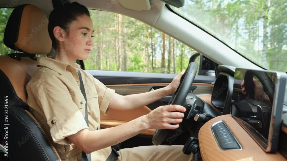 Brunette woman turning on favourite music on car touchscreen display ready for driving on road. Businesswoman in anticipation from trip Brunette woman turning on favourite music on car touchscreen display ready for driving on road. Businesswoman in anticipation from trip