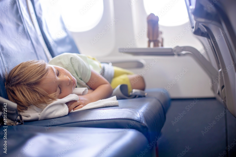 Cute preschool child, flying on a long distant flight, sleeping in the airplane Cute preschool child, flying on a long distant flight, sleeping in the airplane