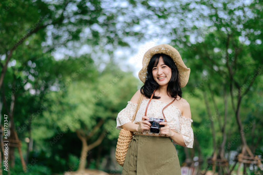 Portrait of asian young woman traveler with weaving hat and basket and a camera on green public park nature background. Journey trip lifestyle, world travel explorer or Asia summer tourism concept. Portrait of asian young woman traveler with weaving hat and basket and a camera on green public park nature background. Journey trip lifestyle, world travel explorer or Asia summer tourism concept.