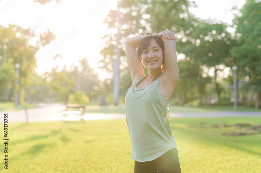 Female jogger. Fit young Asian woman with green sportswear stretching muscle in park before running and enjoying a healthy outdoor. Fitness runner girl in public park. Wellness being concept