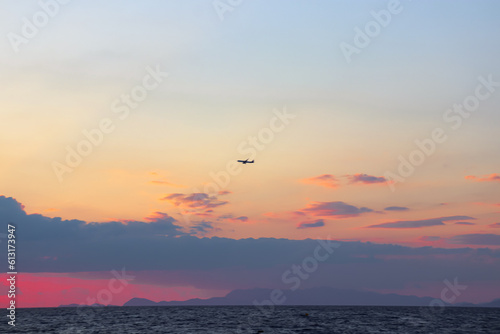 Single plane flying through the clouds at sunset at Paralia Ixia beach off Rhodes city 