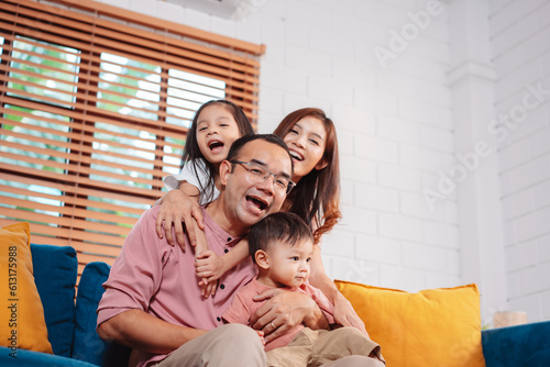 Happy asian family enjoying weekend time relax on couch playing together at home.