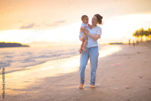 Mother and baby on tropical beach at sunset. © famveldman