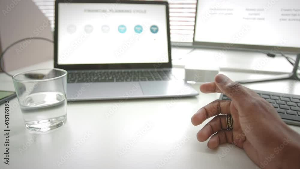 POV of unrecognizable man using digital tablet and laptop computer with business slide presentation while working on corporate project at desk in office
