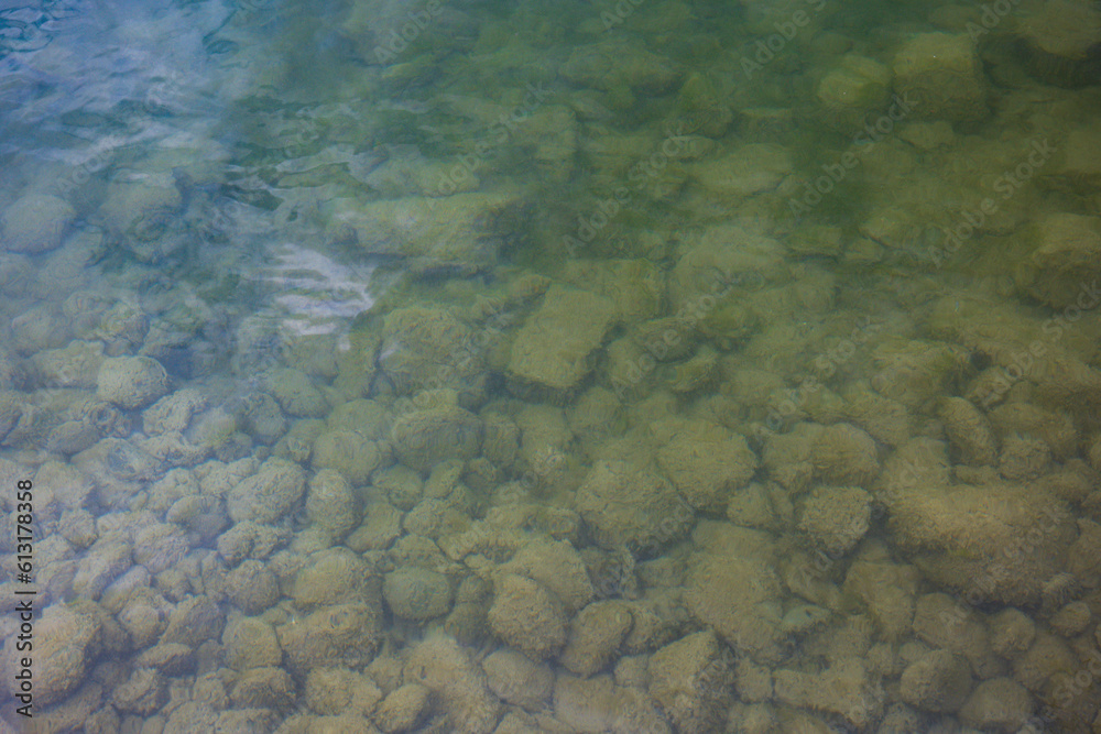 Moss covered rocks under cloudy river water. Top view, no people