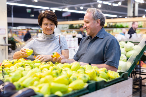 Mature woman and man selecting vegetables in greengrocer