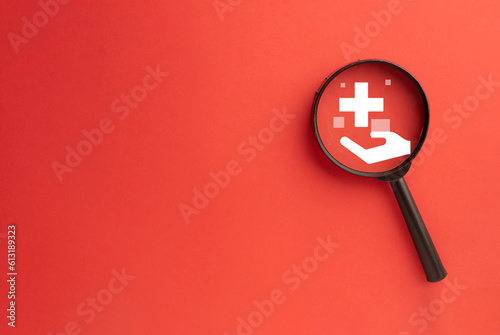 Obraz na plátně Magnifying glass focus on healtcare and medical insurance icon with copyspace over red background idea for Healthcare and Insurance,medical