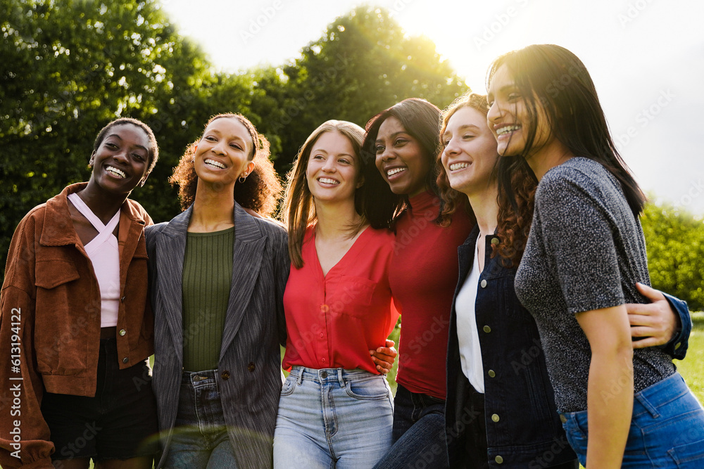 Young multiracial women having fun outdoor - Diverse female friends hugging each other during summer vacations at city park - Focus on center faces