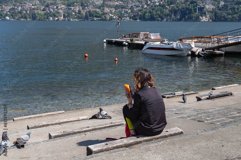 young woman sitting on the steps at the lake and looking at cell phone