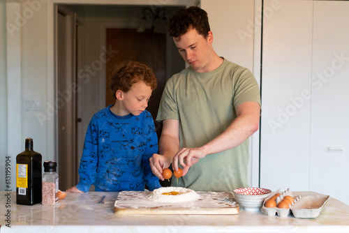 A young dad teaching his son how to crack an egg to make some fresh pasta dough.