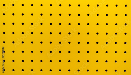 Yellow plastic perforated panel texture. Seamless tile abstract background. Pegboard.