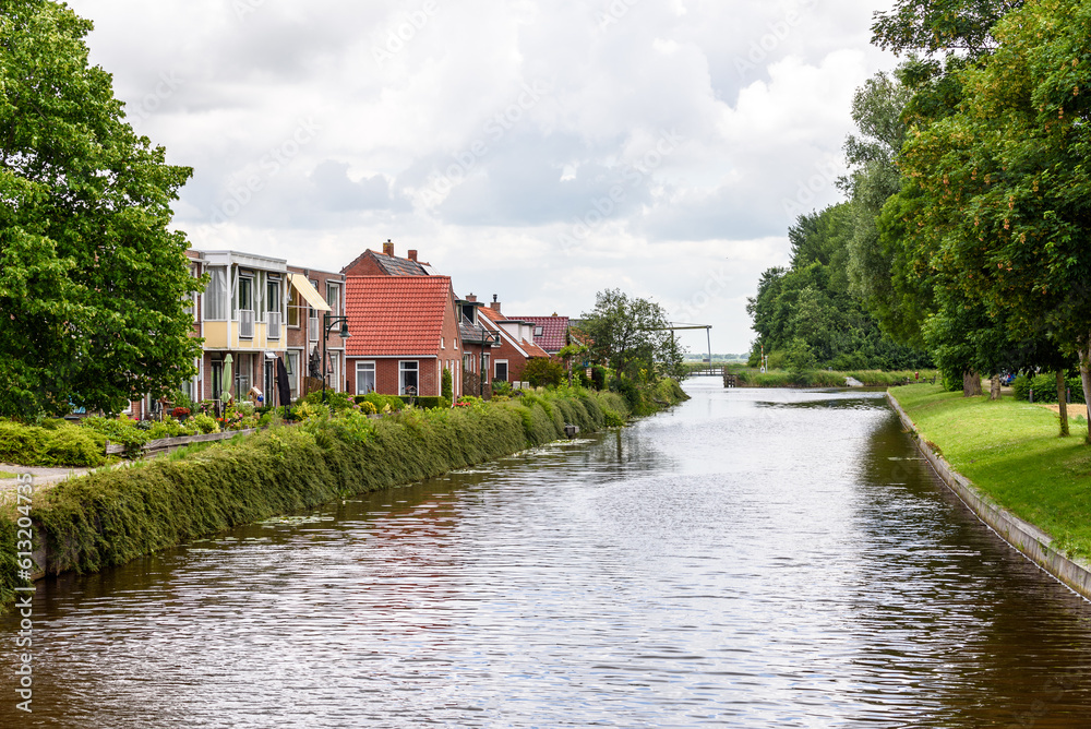 Houses along a canal in the countryside of Netherlands on a cloudy summer day