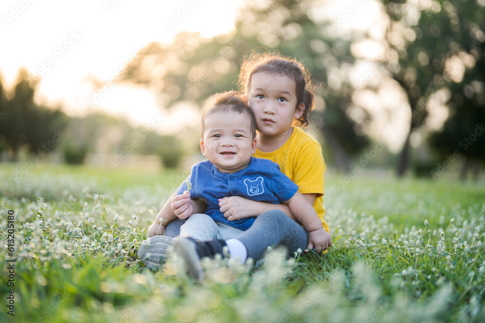 Fototapeta premium Little boy and girl sitting on the grass