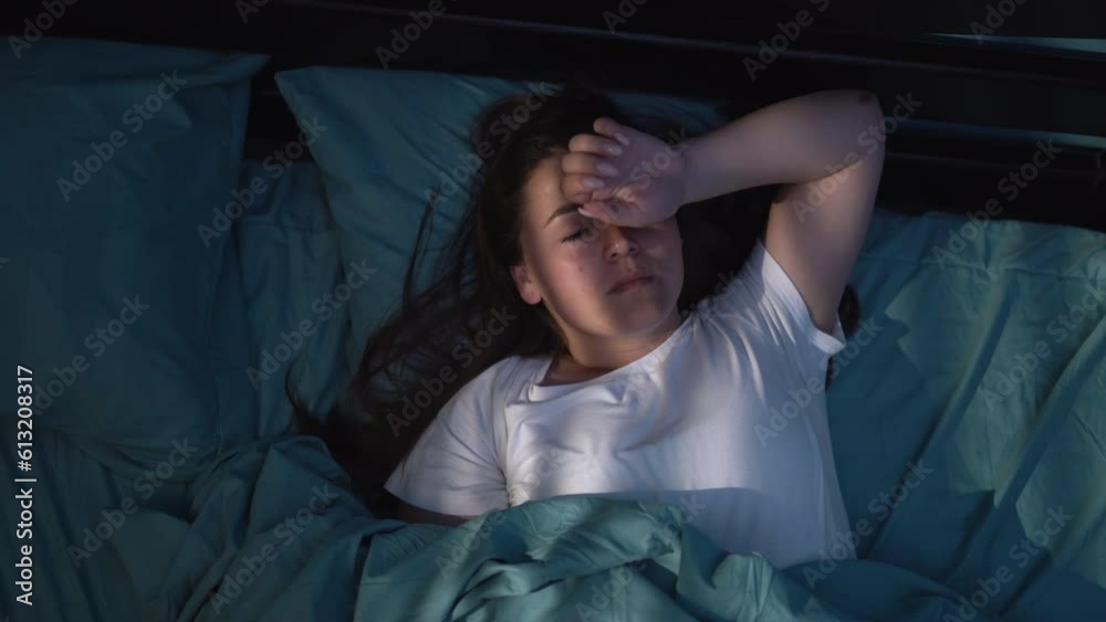 Sleepless young woman lying in bed at night, suffering from insomnia. People, bedtime and rest concept Sleepless young woman lying in bed at night, suffering from insomnia. People, bedtime and rest concept
