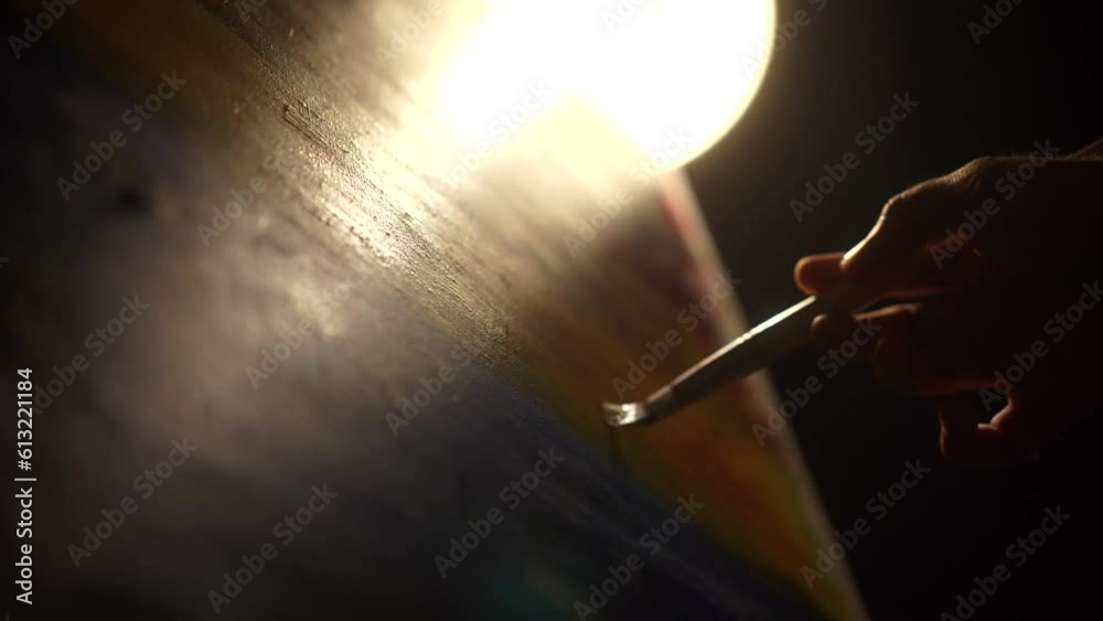 Close-up Moving Paint brush holding on hand of artist and painting on canvas work art with color oil painting at dark room workshop. Artist works and Creative on Abstract Oil Painting at night.
