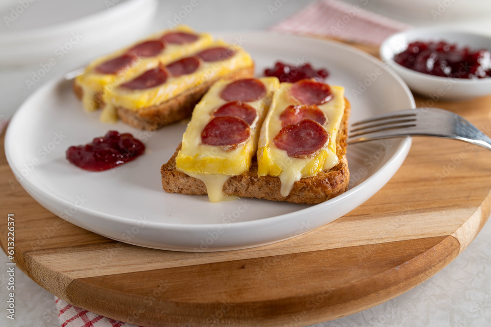 Melted brie or camembert with spanish salami on toast with cranberry sauce Melted brie or camembert with spanish salami on toast with cranberry sauce