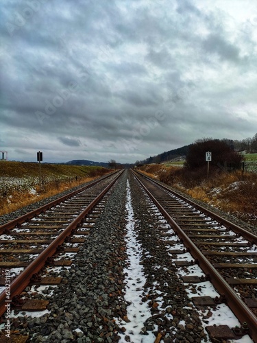 two railway tracks run side by side in winter with snow and cloudy sky (always along the railway line)