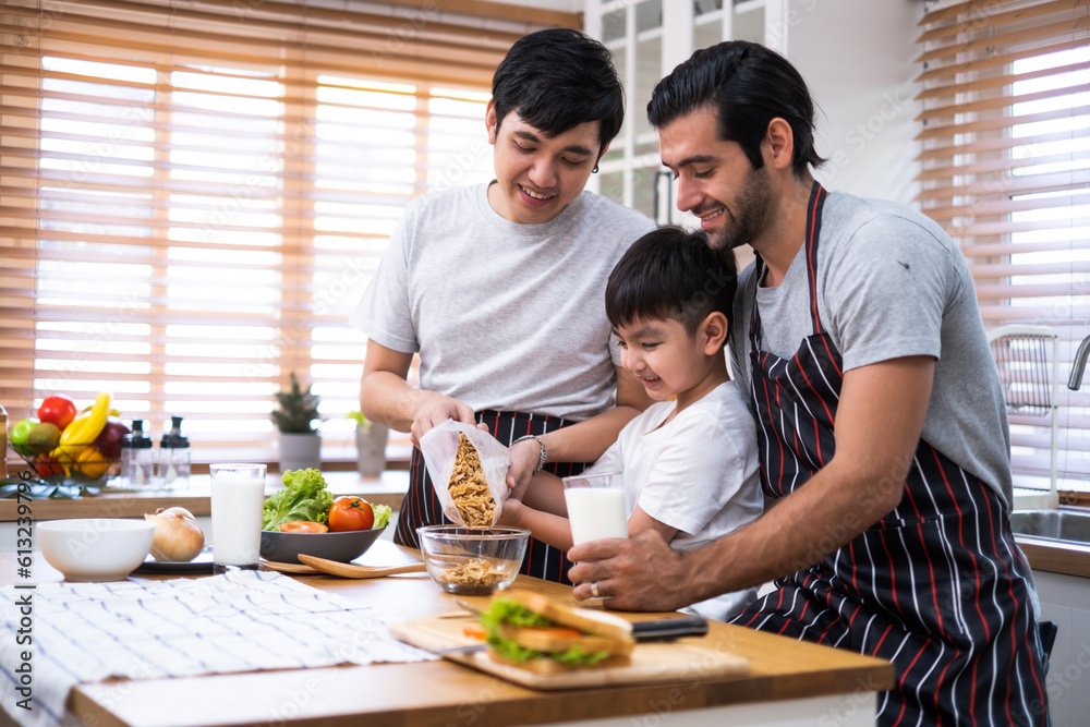 A couple of gays and adopted son family preparing meal together with fun happiness and laughing in kitchen at home, Boy pouring cerial in a glass bolw.