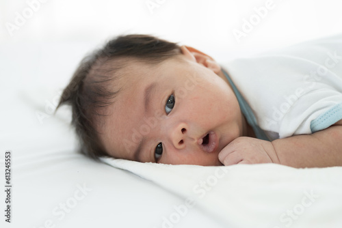 Newborn baby sleeping on blanket on white bed. Infant lying on white bed. Asian newborn baby sleeping in prone position. Asian infant