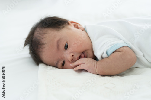 Newborn baby sleeping on blanket on white bed. Infant lying on white bed. Asian newborn baby sleeping in prone position. Asian infant