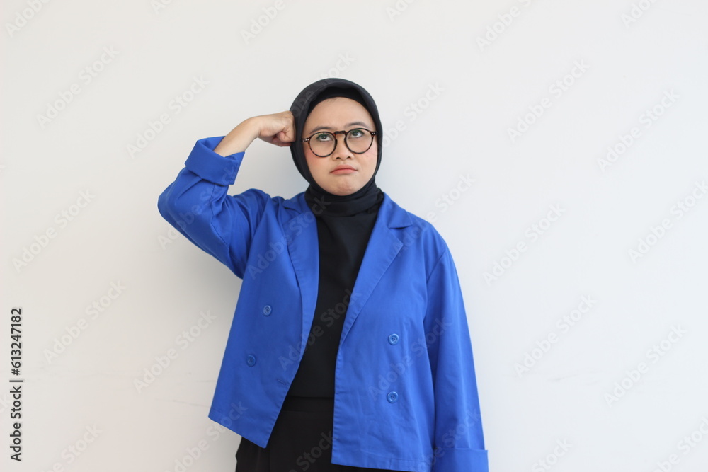 beautiful young Asian Muslim woman, wearing glasses and blue blazer with stressed expression while clenching fist on head beautiful young Asian Muslim woman, wearing glasses and blue blazer with stressed expression while clenching fist on head