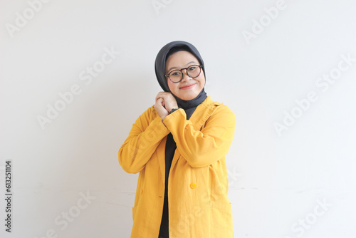 Young beautiful Asian Muslim woman, wearing glasses and yellow blazer with happy smiling face expression