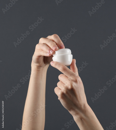 Homan applies cream from white tube to her hands. Template for design. Skin care