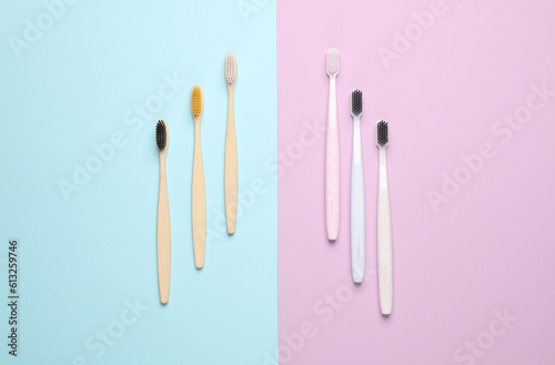 Plastic and eco bamboo toothbrushes on pastel background. Top view