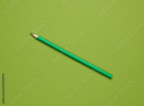 Green pencil on green background. Minimalism