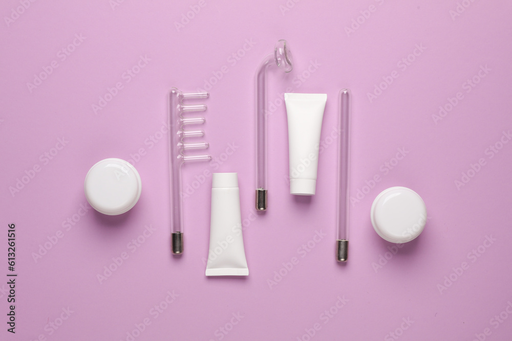 Acne treatment. Nozzles for local darsonvalization with cream jars and tubes on a purple background. Beauty concept. Flat lay