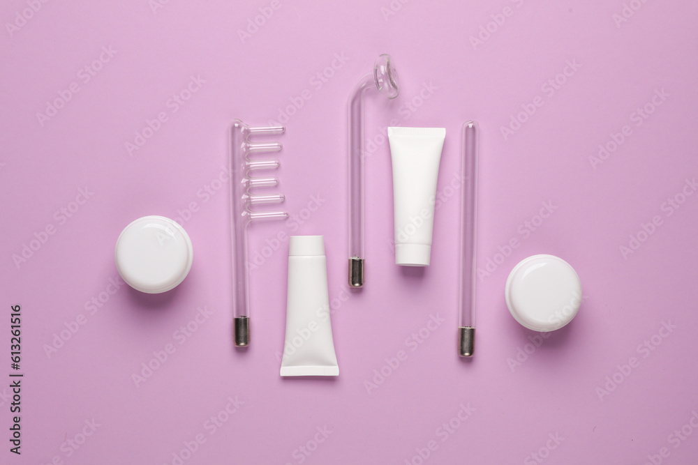 Acne treatment. Nozzles for local darsonvalization with cream jars and tubes on a purple background. Beauty concept. Flat lay Acne treatment. Nozzles for local darsonvalization with cream jars and tubes on a purple background. Beauty concept. Flat lay