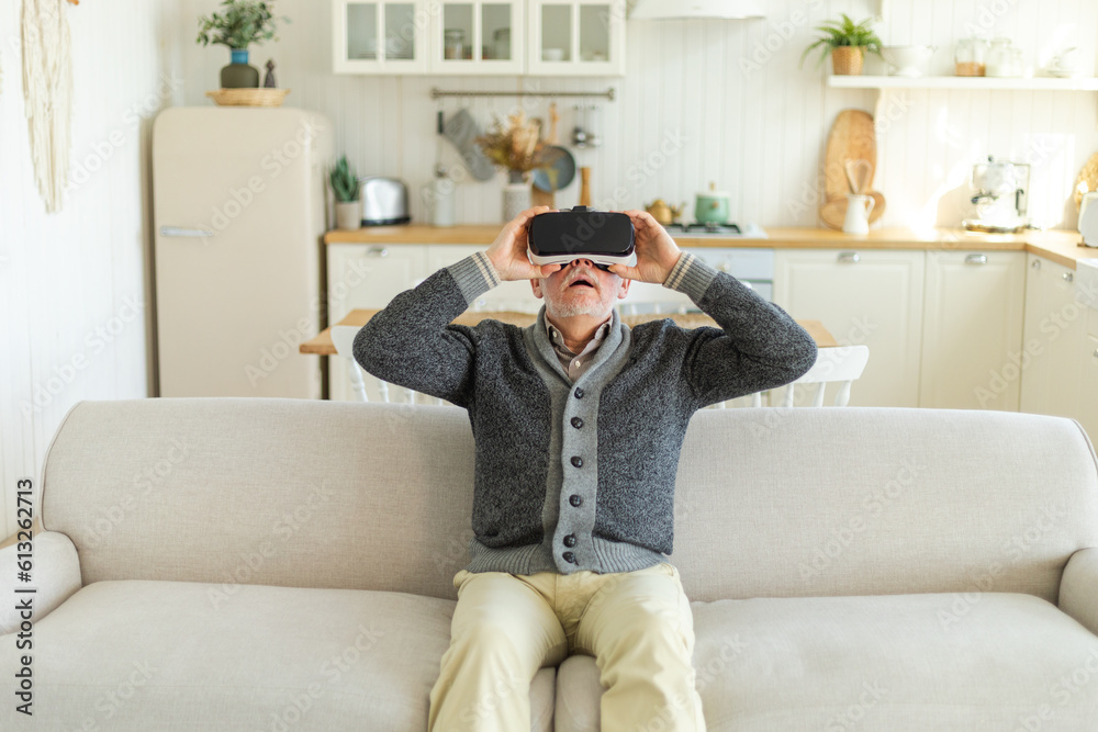 Excited mature senior man wearing using virtual reality metaverse VR glasses headset at home. Grandfather touching air during VR experience on virtual reality helmet. Simulation hi-tech videogame Excited mature senior man wearing using virtual reality metaverse VR glasses headset at home. Grandfather touching air during VR experience on virtual reality helmet. Simulation hi-tech videogame