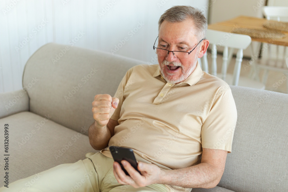 Middle aged senior man euphoric winner with smartphone. Older mature grandfather looking at cell phone reading great news getting good result winning online bid feeling amazed. Winning gesture Middle aged senior man euphoric winner with smartphone. Older mature grandfather looking at cell phone reading great news getting good result winning online bid feeling amazed. Winning gesture