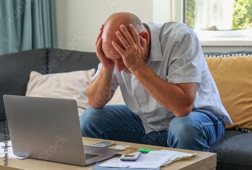  Caucasian man sitting with laptop stressed and confused by financial crisis calculate expense from invoice, bills, credit card, can't pay  debt mortgage or loan. Debt, bankruptcy or bankrupt concept. photo