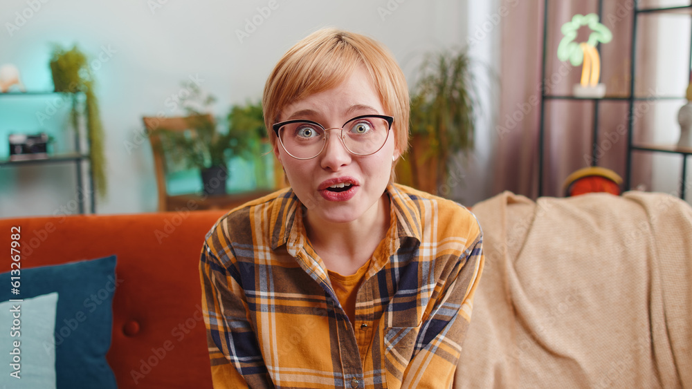 Oh my God, Wow. Portrait of young woman surprised looking at camera with big eyes, shocked by sudden victory, good win news, celebrating sitting on sofa. Excited amazed girl at home room apartment Oh my God, Wow. Portrait of young woman surprised looking at camera with big eyes, shocked by sudden victory, good win news, celebrating sitting on sofa. Excited amazed girl at home room apartment