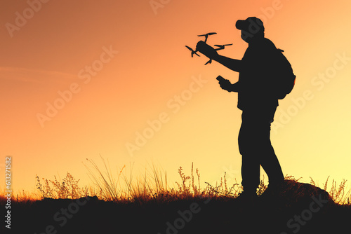 silhouette of a man holding a quadcopter and a smartphone