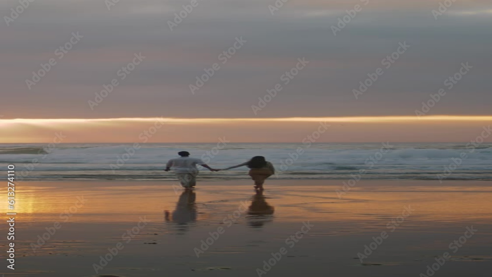 Sweethearts silhouettes walking sunbeams sea. People enjoying date vertical view Sweethearts silhouettes walking sunbeams sea. People enjoying date vertical view