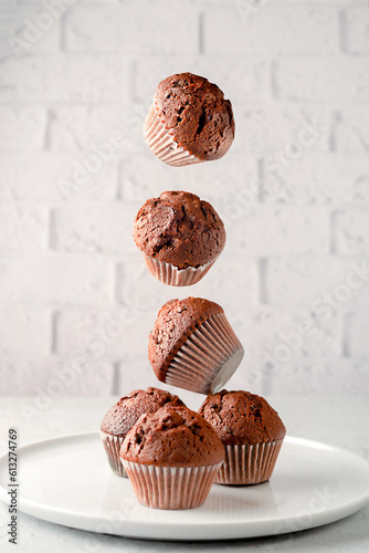 Soft, fluffy, chocolate chip vanilla muffins in paper liners, on pink background.